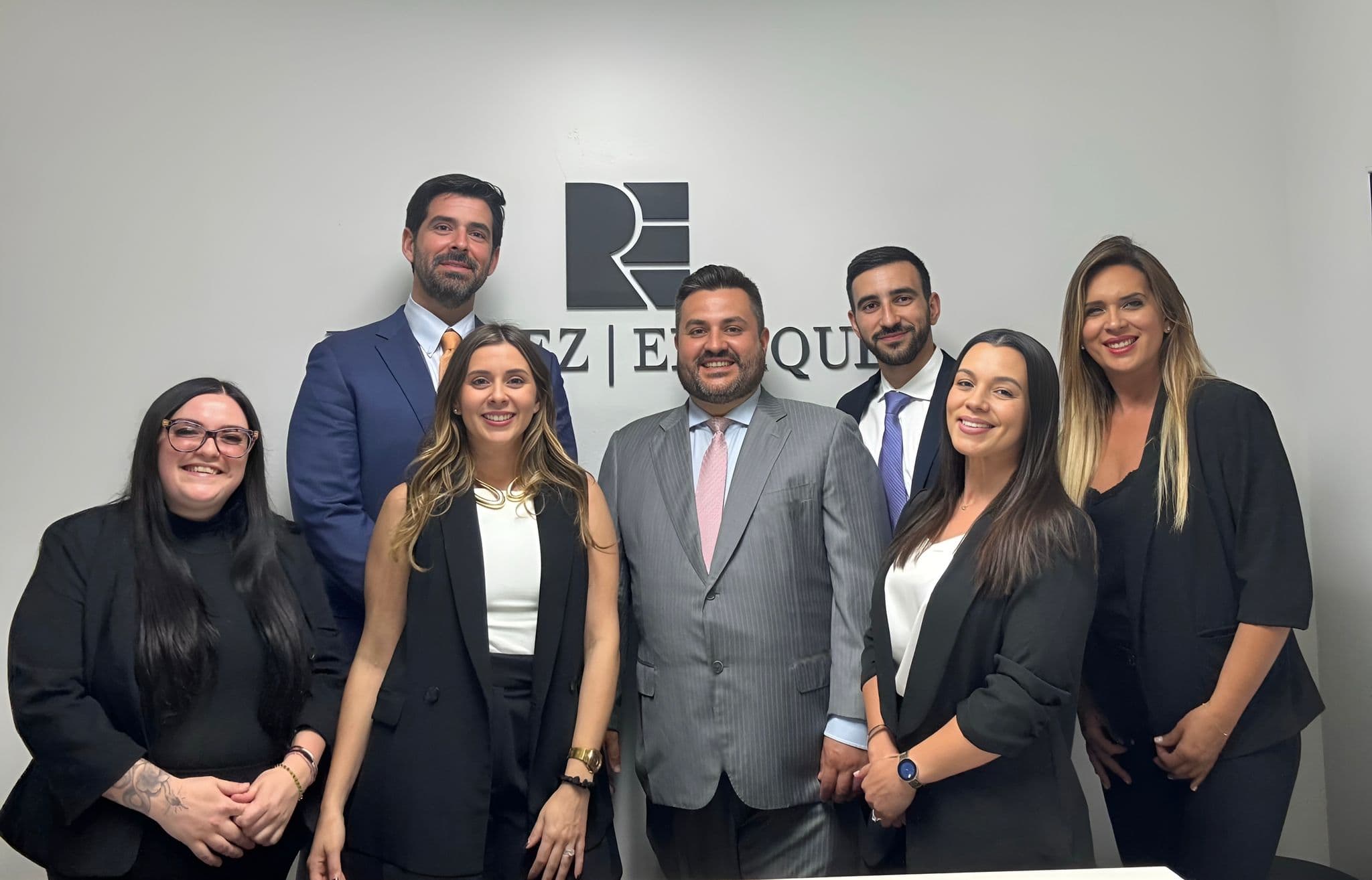 Ramirez Enriquez PLLC team in front of the firm logo